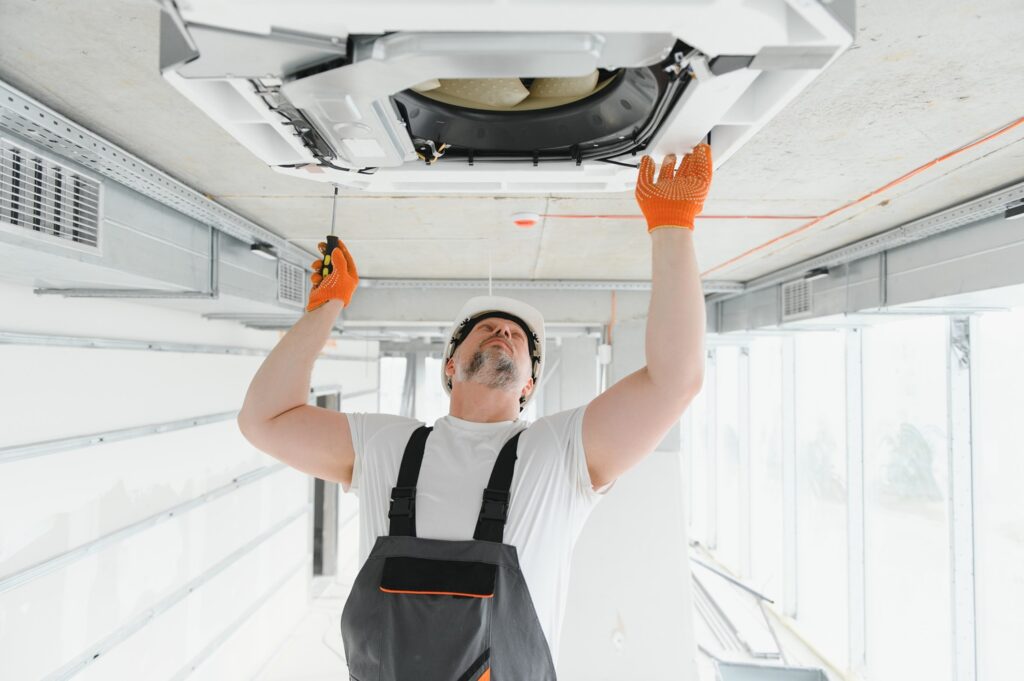 Worker repairing ceiling air conditioning unit